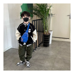 Close-up of kids canvas crossbody bag paired with an olive utility pant and baseball jacket