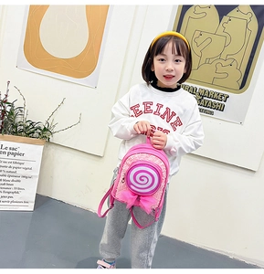 Pink toddler backpack with sequins, lollipop design and bow shown on a young girl