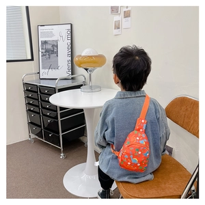 Detail showing the adjustable orange strap and cartoon dinosaur print on the kids chest bag
