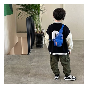 Close-up of children's blue canvas chest bag with orange zipper and fashion text details