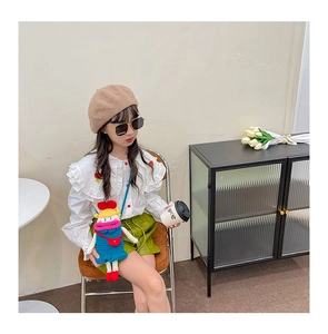 Detail of a handmade colorful crochet doll crossbody bag worn by a young child model