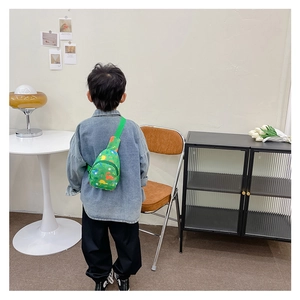 Rear view of a child wearing a green canvas dinosaur print crossbody chest bag