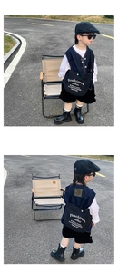 Detail of a black canvas crossbody bag with white lettering for kids outdoors