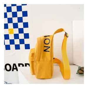 Side view of a bright yellow canvas chest bag for kids with black ION lettering print