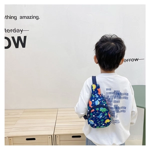 Blue kids chest bag featuring colorful cartoon dinosaur prints worn by a child model
