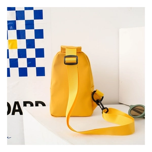 Detail of yellow canvas kids chest bag with adjustable strap on geometric background