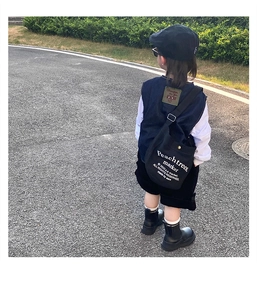 Street style boy in denim vest and black canvas crossbody bag with letter print