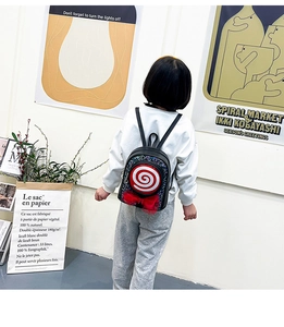 Close-up of kids backpack with colorful sequins, lollipop pattern, and red mesh bow