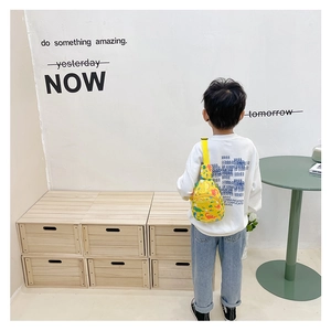 Detail of yellow kids chest bag featuring colorful cartoon dinosaur prints and zippers