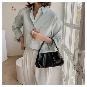 Detail of black pleated cloud bag with knotted handle shown on model's shoulder