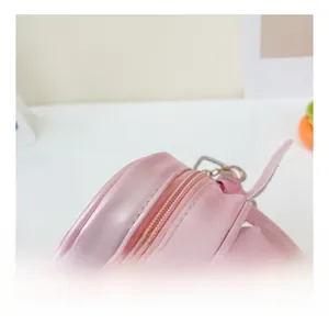 Détail du sac à bandoulière rose à paillettes montrant le zip et les boucles argentées