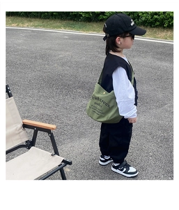 Detail of green canvas crossbody bag for kids with black letter print and utility style