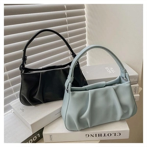 Close-up of ruched cloud bags in black and light blue on white books in natural light