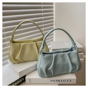 Detail of light blue and yellow pleated cloud bags showing premium leather texture