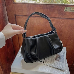 Minimalist black pleated cloud bag shown on vintage background with handle detail