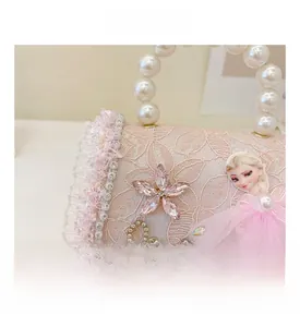 Détail du sac en dentelle rose avec anse en perles, chaîne dorée et motif princesse