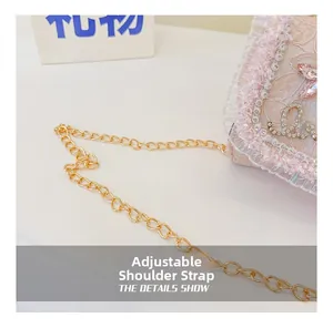 Détail du sac en dentelle rose montrant des lettres en cristal et une chaîne dorée