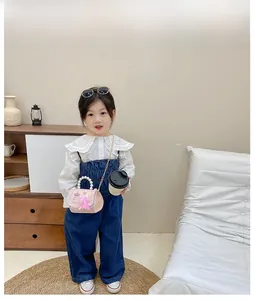 Sac à main rose pour fille avec poignée en perles et chaîne dorée porté par un modèle