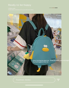 Detail view of a dark teal cartoon duck backpack with yellow wing and beak accents