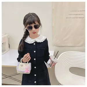 Fillette avec mini sac à main crème, poignée en perles et paillettes pour enfants