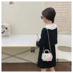 Détail d'un enfant portant un sac à main perle sirène avec chaîne dorée en intérieur