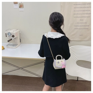 Fillette portant un sac à perles sirène blanc avec pendentif poupée et chaîne dorée