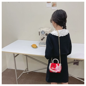Détail sac à bandoulière rouge pour enfant avec poignée en perles et chaîne dorée