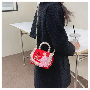 Détail du sac de princesse rouge avec poignée en perles et chaîne dorée sur l'épaule