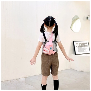 Pink shark-shaped canvas chest bag for kids shown on child model in a studio setting