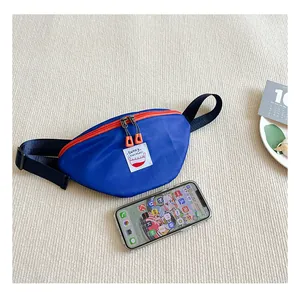 Detail of blue and orange nylon kids fanny pack with a contrast zipper on textured rug