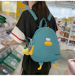 Detailed side view of cartoon duck backpack featuring 3D bill and feet on teal fabric