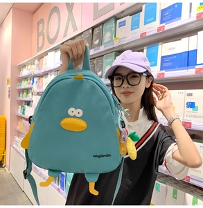 Detailed view of the cute blue duck backpack with embroidered eyes and banana charm