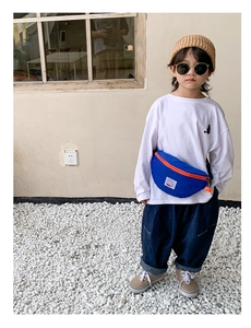 Close-up of navy canvas kids chest bag with orange zipper and minimalist white brand tag