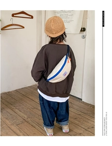 Kids minimalist canvas chest bag featuring cream fabric with blue zipper and orange pulls