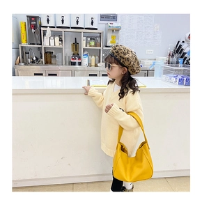 Close-up of bright yellow mini Hobo bag held by a stylish girl wearing a leopard beret