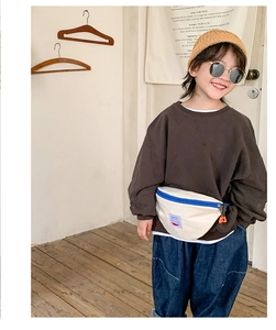Kid's canvas waist bag in beige with blue zipper detail shown on a stylish outfit model