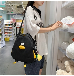 Detail of cute black duck canvas crossbody bag with 3D eyes and feet on retail shelf