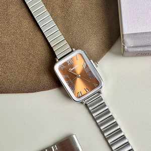 Detail of vintage rectangular watch with orange dial and silver stretch metal band