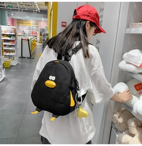 Detail showing back view of cute black penguin backpack with yellow decorative feet