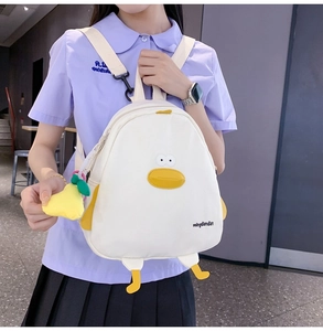 Detail view of a white cartoon duck backpack with plush yellow feet and embroidered eyes