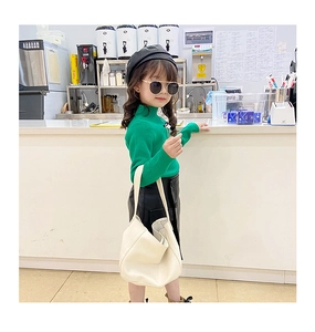 Girl's fall fashion outfit featuring cream moon bag, green knit sweater, and leather skirt