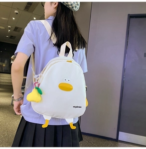 Detail view of a white canvas chick backpack featuring cartoon eyes and yellow duck feet