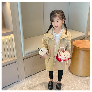 Girl model wearing khaki trench coat with red bow pearl handle chain crossbody bag