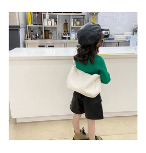Fashionable girls cream-colored crescent bag shown worn with a green knitted sweater