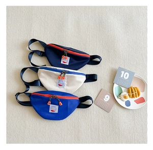 Close-up of children's canvas waist bags in navy, white and blue with adjustable straps