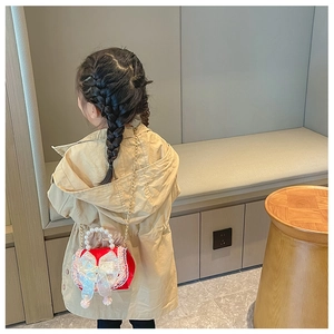 Girl wearing a red crossbody bag with a white lace bow and pearl handle detail