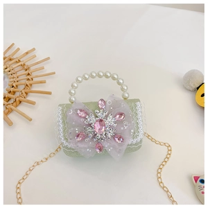 Detail der hellgrünen Mini-Handtasche mit Perlengriff, lila Schleife und Schneekristall