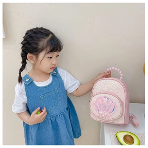 Close-up of pink sequined kids backpack with shell patch and pearl bead handle
