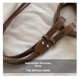 Detail of adjustable dark brown leather shoulder strap with gold buckle and fine stitching