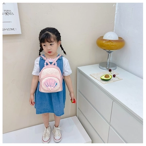 Toddler girl wearing pink sequin backpack with pearl shell detail in minimalist room